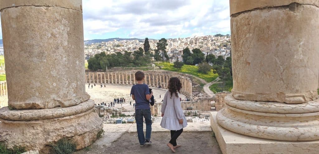 Two kids standing between massive Roman columns in Jerash, Jordan