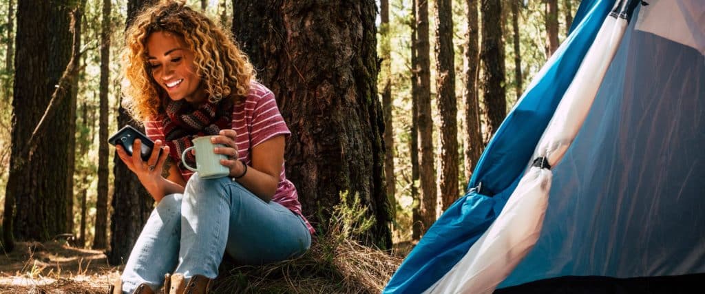 A woman smile at her phone while camping.