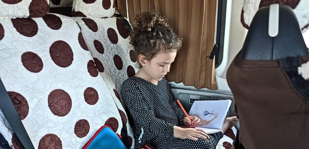 A girl drawing a picture inside a transfer van.