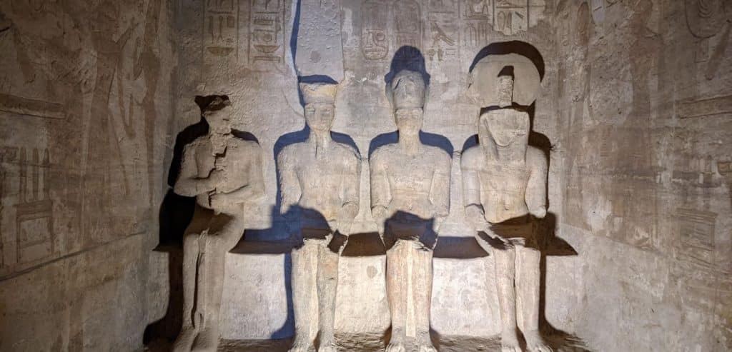 A light shining on statues of Ramses inside Abu Simbel