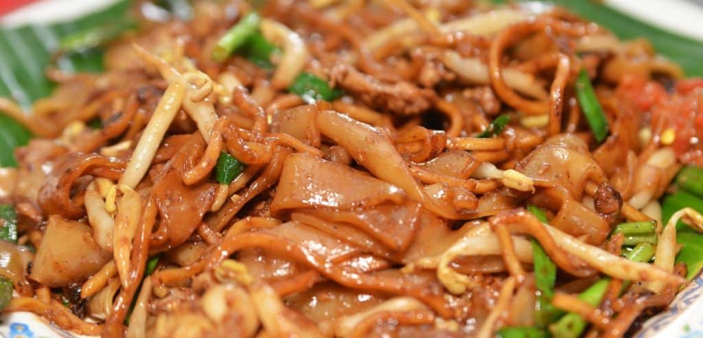 A plate of wide rice noodles stir-fried with other popular ingredients.
