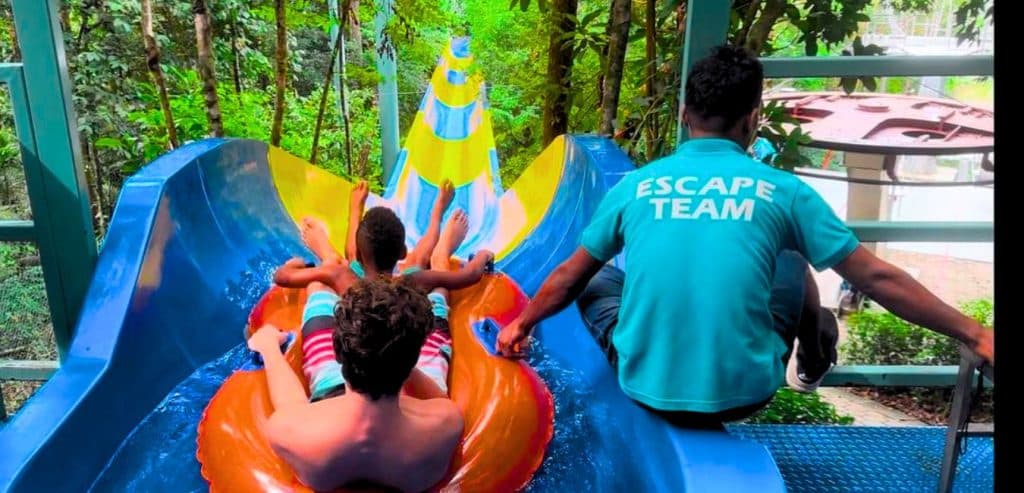Two boys get ready to go down a waterslide. 