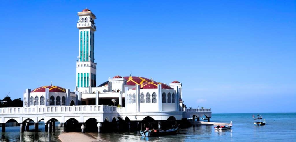 A mosque built on concrete pylons gives the illusion that it is floating on the water. 
