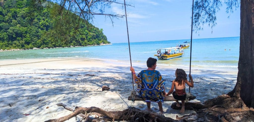 A mother and daughter share a swing on Monkey Beach in Penang National Park.