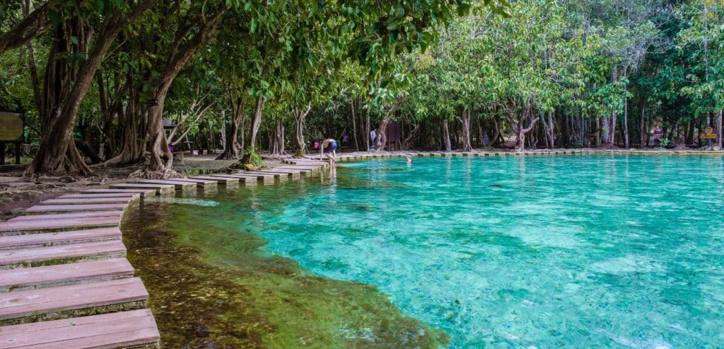 A wooden path running along the edge of the Emerald Pool's turquoise blue waters.