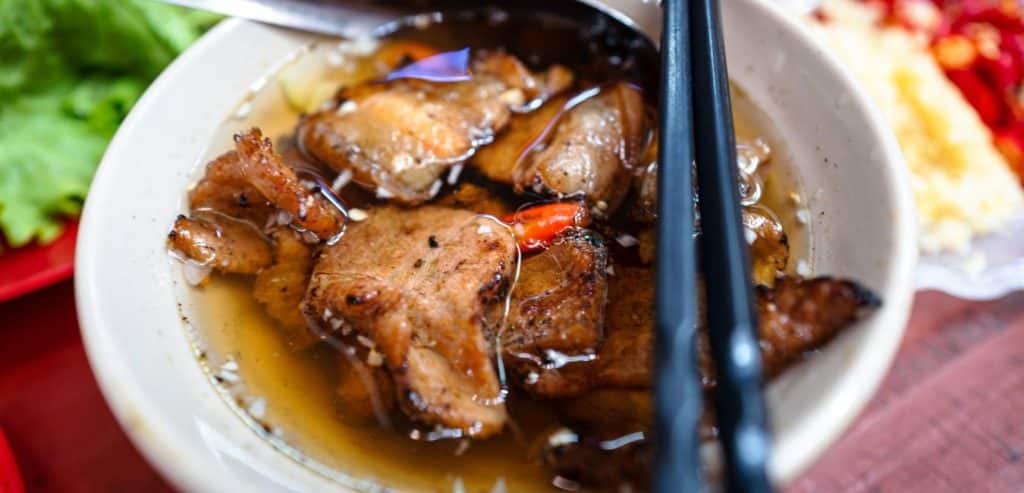A bowl of bun cha with chopsticks laying across it.