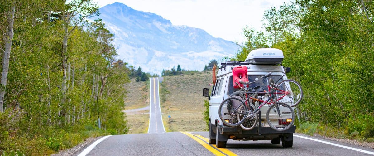 A van driving down the road towards mountains in the distance.