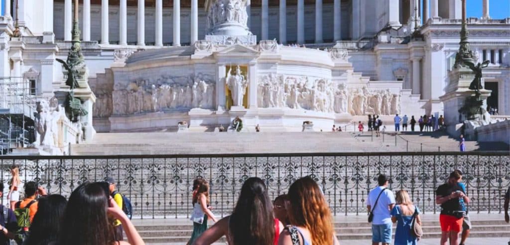 People take pictures of the Victor Emmanuel II Monument from the street in Rome