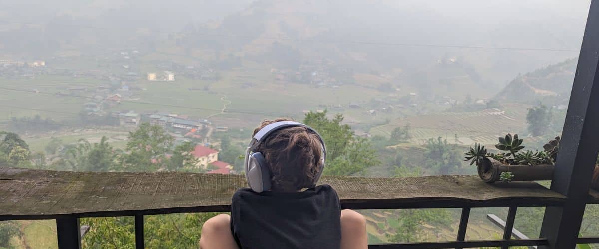 A boy listening to headphones while watching the rain in Sapa
