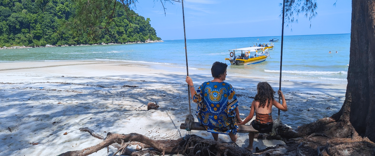 Two people sitting on a swing at Monkey Beach in Penang.