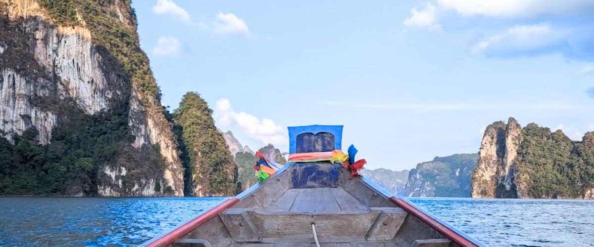 The prow of a Thai longboat with limestone formations in front of it
