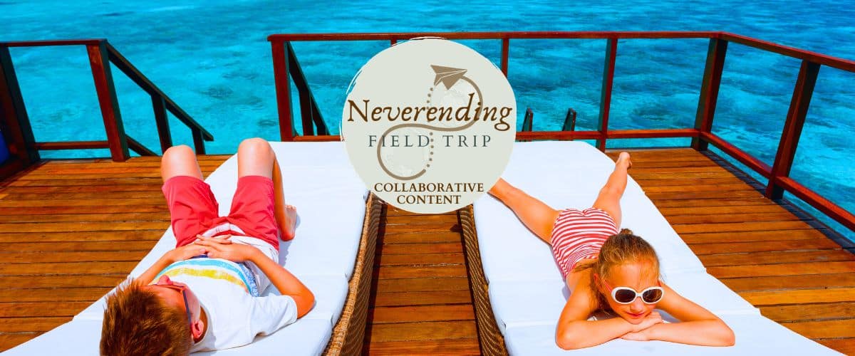 Two kids relaxing on loungers overlooking blue waters.