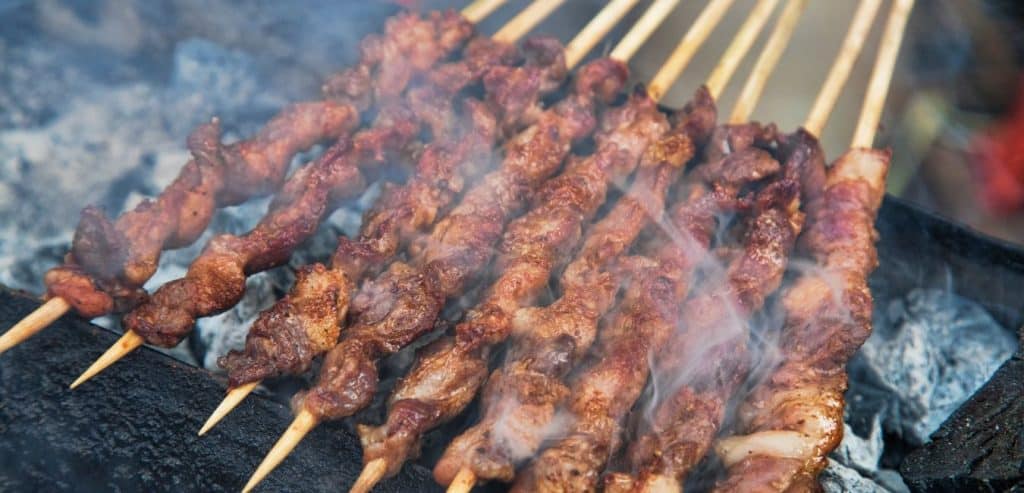 Grilled meat skewers over charcoal